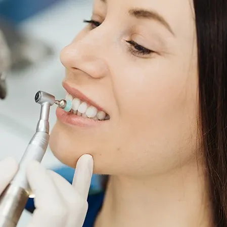 A woman smiling while a dentist cleans her teeth