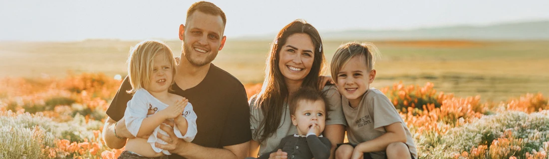 Happy Family With Three Kids Outside in a Field at Sunset